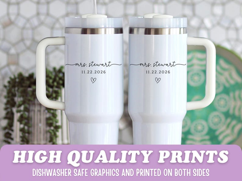 May include: Two white travel mugs with silver rims and white handles. Each mug is personalized with the text "mrs. stewart", the date "11.22.2026", and a heart symbol. The mugs have a modern design and are suitable for hot or cold beverages.
