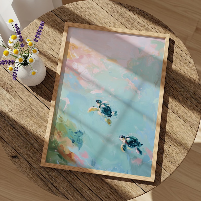 May include: A framed art print featuring two sea turtles swimming in a turquoise ocean. The artwork has a watercolor style with soft pink, blue, and green hues. The frame is made of light-colored wood. A vase of flowers sits on a wooden table.