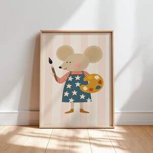 Może przedstawiać: Oprawiony wydruk przedstawiający mysz z kreskówki jako artystę. Myszka ma na sobie niebieską sukienkę z białymi gwiazdami i czerwono-białą koszulę w paski. Trzyma pędzel i żółtą paletę z kolorową farbą. Tło ma różowe i białe pionowe paski.