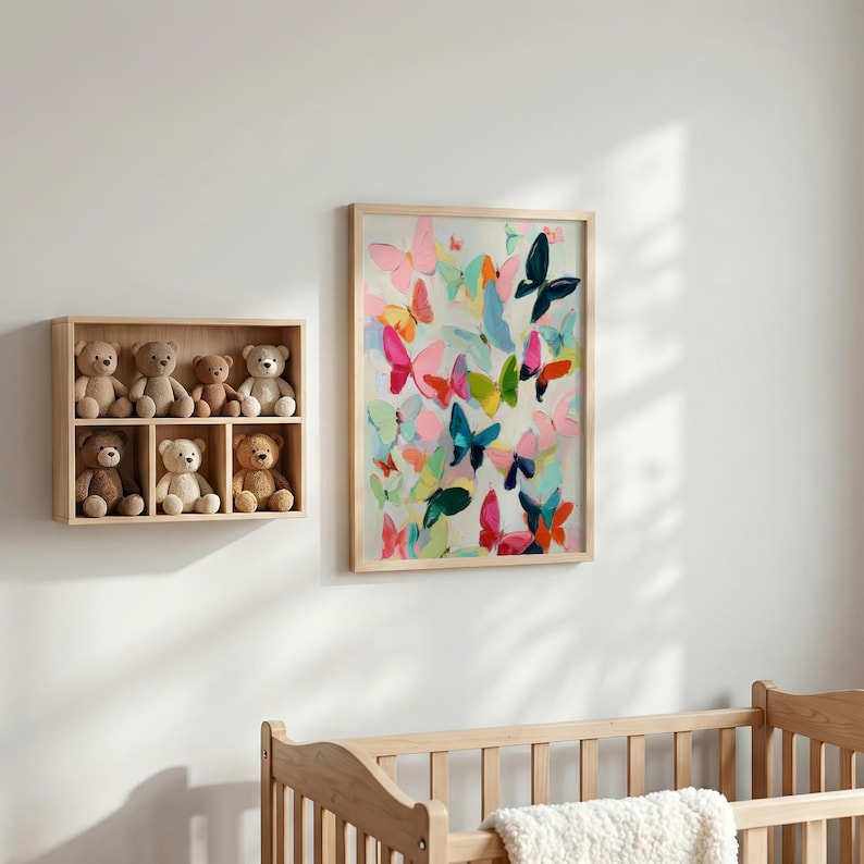May include: A colourful butterfly art print in a light wood frame adorns a white wall. The artwork showcases butterflies in pink, blue, green, and orange. A wooden shelf with six teddy bears is positioned to the left.