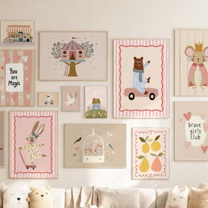 Può includere: Una composizione a parete di varie stampe artistiche rettangolari con illustrazioni di animali, una casa sull'albero, frutta e testi tra cui 'You are Magic' e 'brave girls club' in tenui tonalità pastello rosa, crema e marrone su una parete chiara.