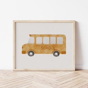 Op de afbeelding: Waterverfillustratie van een gele schoolbus met het woord "SCHOOL" op de zijkant. De bus heeft zwarte wielen en staat tegen een witte achtergrond, omlijst in een licht houten frame. Perfect voor kinderkamerdecoratie.