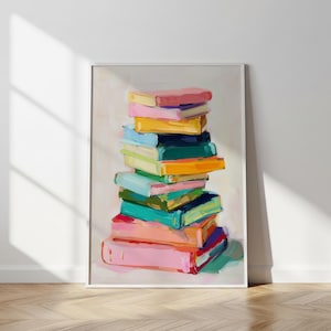 Puede incluir: Una impresión artística enmarcada que presenta una pila de libros coloridos. Los libros están pintados en una vibrante paleta de rosas, amarillos, azules y verdes, con pinceladas visibles. La obra de arte se muestra sobre un fondo neutro.
