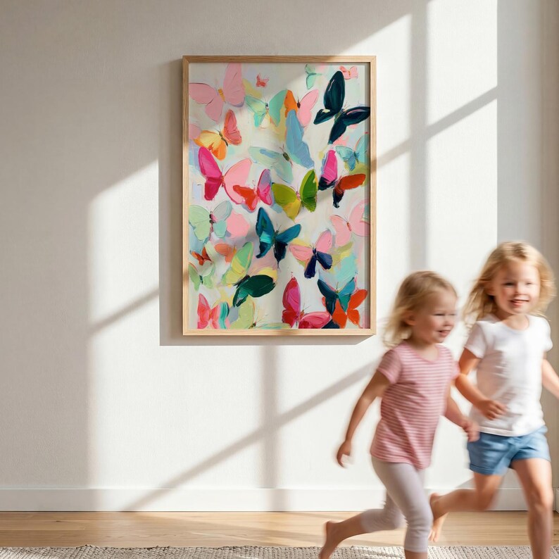May include: A framed artwork displaying a collection of colourful butterflies in shades of pink, blue, green, and orange. The butterflies are painted in a loose, expressive style, creating a sense of movement and joy. The frame is a light wood colour.