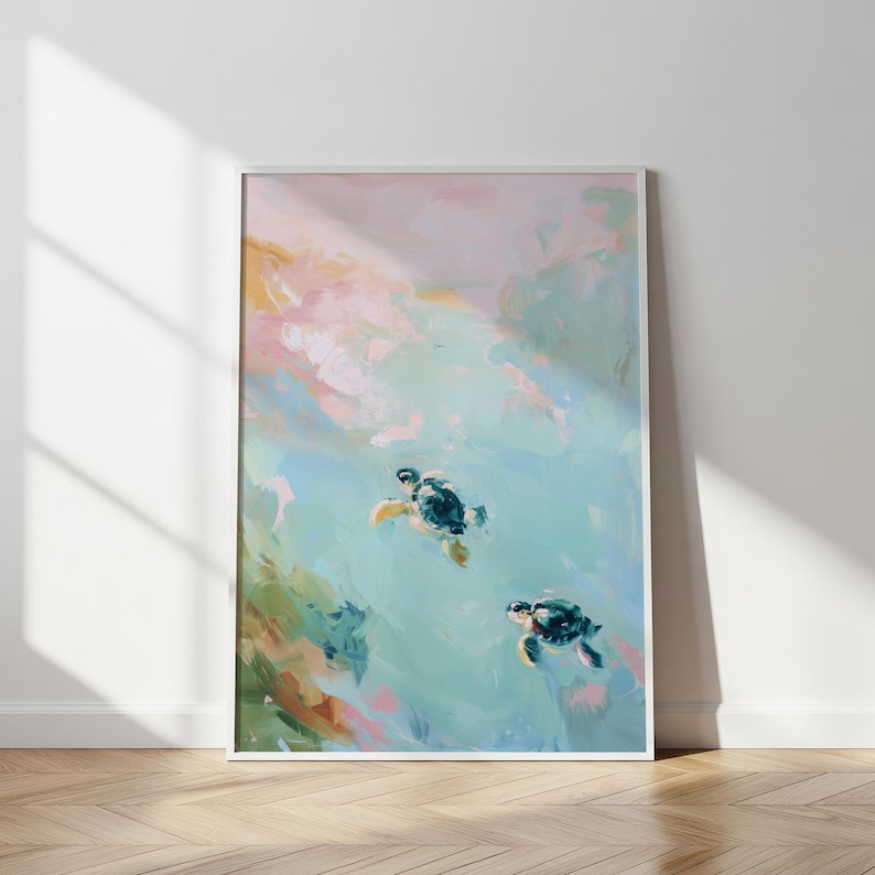 May include: Framed art print featuring an abstract painting of two sea turtles swimming in turquoise water. The artwork has a soft, painterly style with pastel colors of pink, blue, and green. The print is displayed in a white frame.