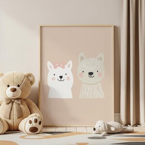 May include: A framed print featuring two cartoon animal faces on a light pink background. One is white with a pink bow, the other is beige. A teddy bear and a stuffed dog are in the foreground.