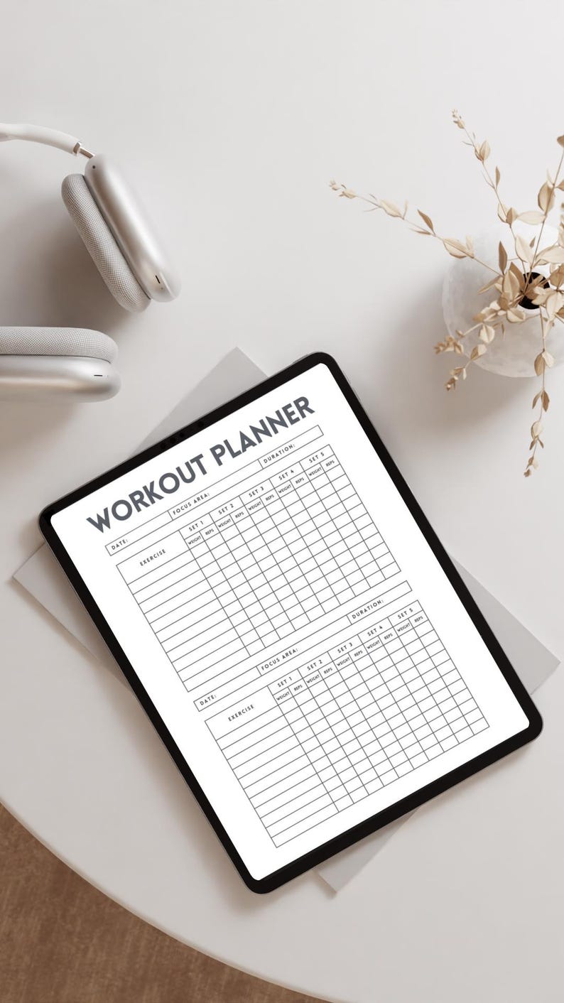 May include: A digital workout planner on a tablet with the title "WORKOUT PLANNER" in bold, black letters. The planner has sections for date, exercise, focus area, sets, reps, weight, and duration. White headphones and a decorative plant are in the background.