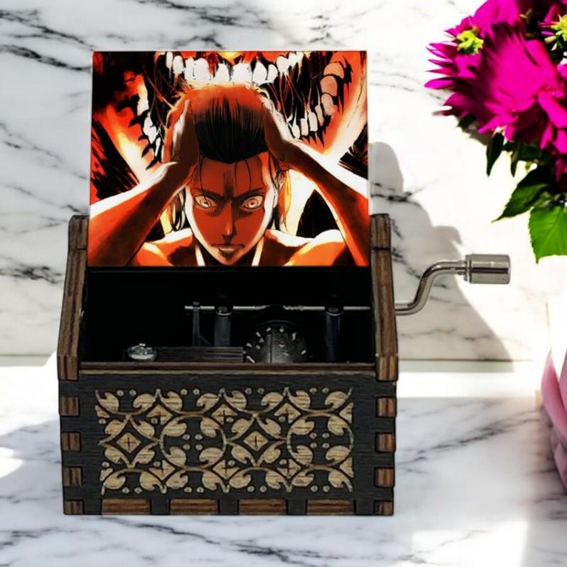May include: A wooden music box with a hand-crank on the side. The lid is open and features a colorful image of a character from the anime Attack on Titan. The box has a decorative design on the front.