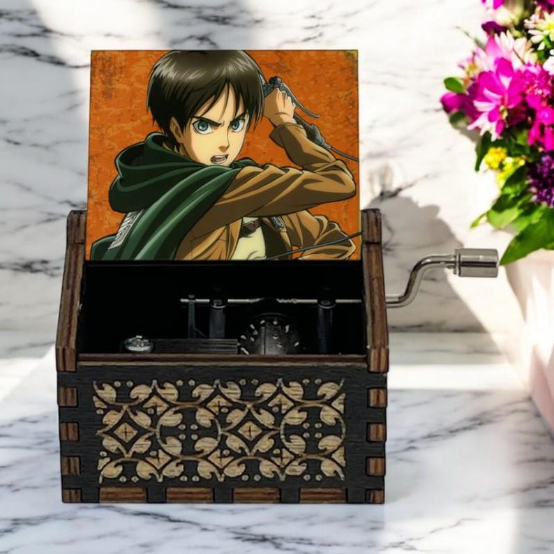 May include: A wooden music box with a hand-crank on the side. The lid features a colorful image of an anime character with brown hair and green eyes, holding a sword. The box has a decorative design on the front.