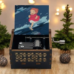 May include: A wooden music box with a black base and a gold pattern. The lid shows a cartoon character running on water. The box has a silver crank and visible mechanical components. The box is decorated with Christmas trees.