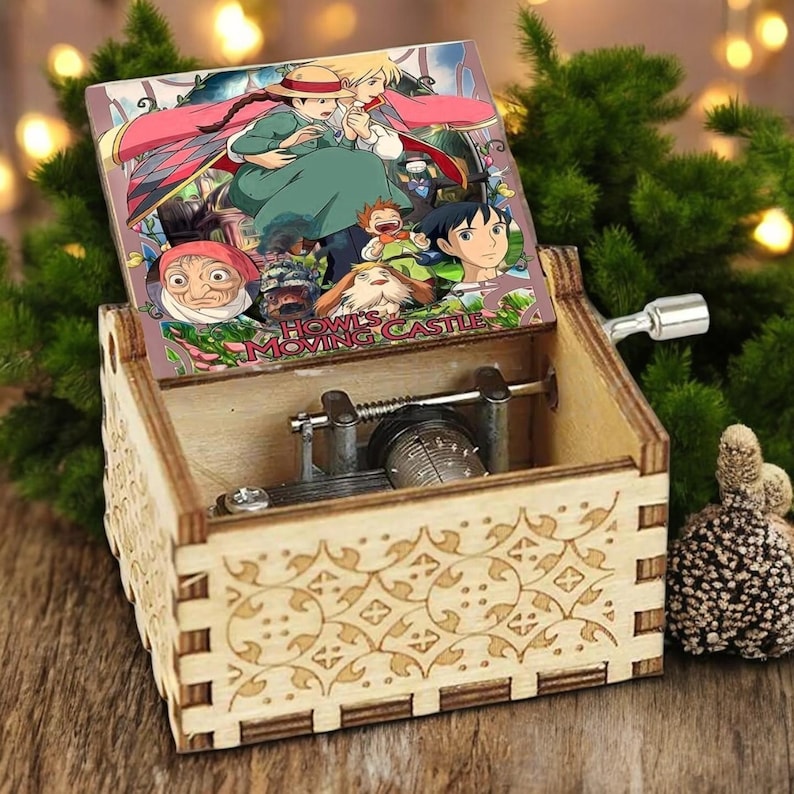May include: A wooden music box with a hand-painted image of characters from the animated film "Howl's Moving Castle". The music box has a detailed floral design on the front and a crank on the side.