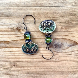 May include: Two green and gold owl-shaped ornaments with glass beads and black wire hangers.