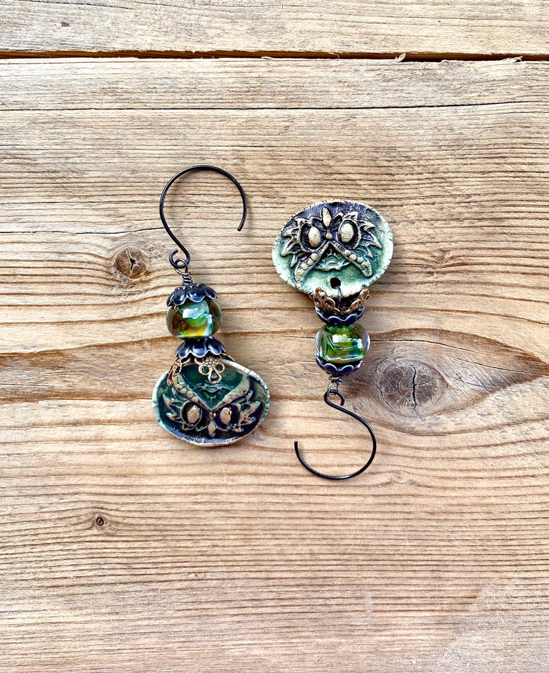 May include: Two green and gold owl-shaped ornaments with glass beads and black wire hangers.