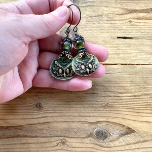 May include: Green and gold owl earrings with black beads and wire hooks.