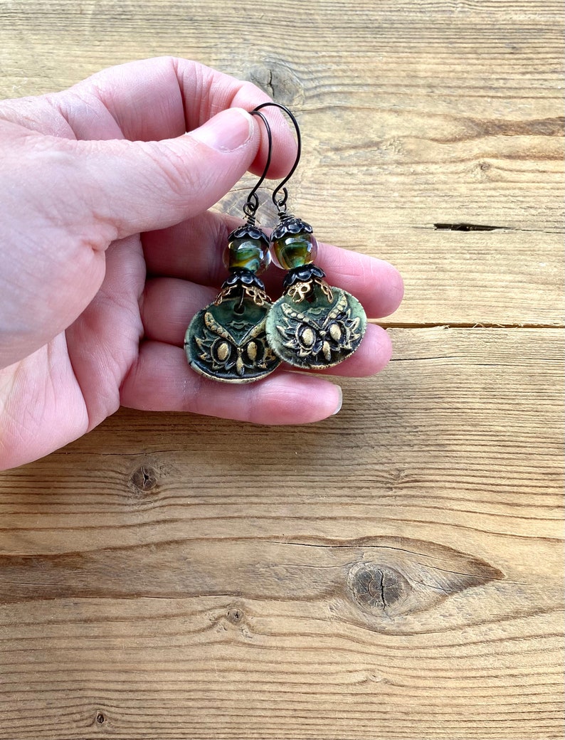 May include: Green and gold owl earrings with black beads and wire hooks.