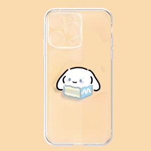 May include: Clear phone case featuring a cartoon character with a white body, black outlines, and blue accents. The character is holding a blue and yellow cake. The case is designed to fit a smartphone.