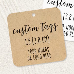 May include: Two square custom tags with rounded corners. One tag is light brown with the text "custom tags" and "1.5 (3.8 CM)". The other tag is white with the text "custom tags" and "1.5 (3.8 CM)". Both tags have a hole at the top.