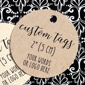 May include: Two round, brown paper gift tags with a hole punched in the top. The tags are 2 inches in diameter and have the text 'custom tags 2' (5 CM) YOUR WORDS OR LOGO HERE' printed on them.