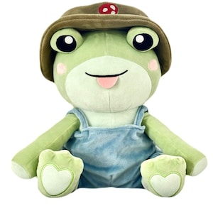 May include: A green plush frog wearing a brown hat with a red mushroom on top and blue overalls. The frog has a big smile and its tongue is sticking out.