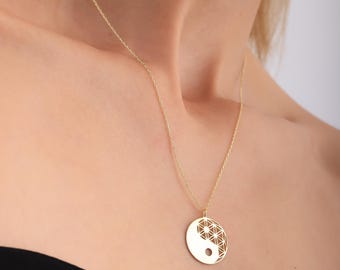 May include: A gold necklace with a round pendant featuring a yin yang symbol with a geometric design inside.