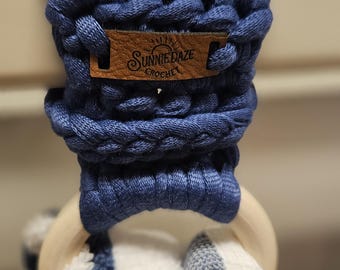 Könnte beinhalten: Ein blauer gehäkelter Handtuchring mit einem Holzring und einem braunen Lederanhänger mit der Aufschrift "Sunnie Daze Crochet".