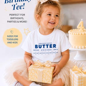 May include: A young child wearing a white t-shirt with the word "BUTTER" printed on it, holding a wrapped gift. The image includes text that says "The Cutest Birthday Tee!" and "Sized for Toddlers and Kids."