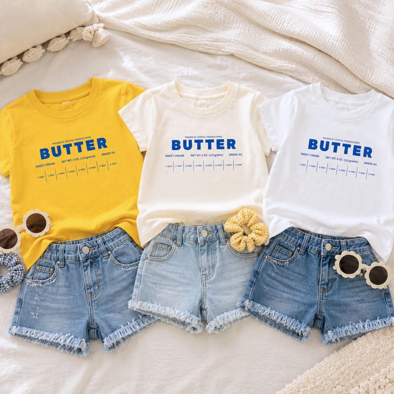 Butter stick label toddler shirts in yellow, white, and cream color options paired with denim shorts for boutique kids fashion styling. Retro foodie birthday shirts inspired by sweet cream baking themes, preschool outfits, and playful family celebrations.