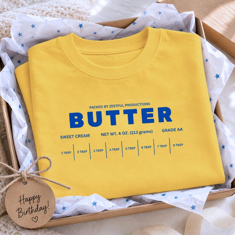 Folded yellow retro kids t-shirt with butter packaging graphic and sweet cream foodie design. Boutique toddler birthday outfit styled for baking parties, preschool celebrations, foodie families, and trendy children’s apparel photography.
