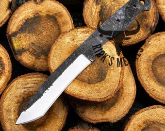 May include: A black and silver knife blade with a textured handle. The blade is silver and the handle is black with three holes. The text "Rik's Me" is visible on the blade. The knife is resting on a bed of wood slices.