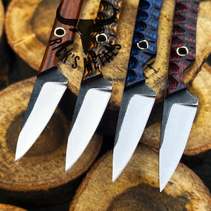 May include: Close-up of four custom knives with various handle designs and polished blades. The handles feature wood grain and patterned resin in shades of brown, blue, and red. The blades are silver and the knives are arranged on wooden slices. The text "Rick's Metals" is visible.