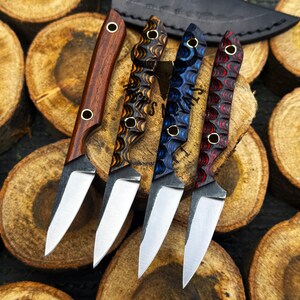 K&ouml;nnte beinhalten: Vier feststehende Messer mit silbernen Stahlklingen und strukturierten Griffen. Ein Griff ist aus glattem braunem Holz, w&auml;hrend die anderen drei geschichtete, gewellte Muster in Orange-Schwarz, Blau-Schwarz und Rot-Schwarz mit je zwei Nieten aufweisen.