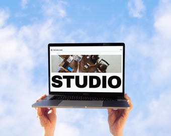 May include: A laptop computer with a bright white screen displaying the word "STUDIO" in black text. The screen also shows a photo of a group of people working together at a table.