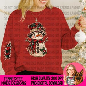 Puede incluir: Una sudadera roja de manga larga con un gráfico central de un muñeco de nieve con sombrero y bufanda de cuadros, decorado con bayas de acebo. La manga izquierda muestra un parche de cuadros a juego y tres botones negros.