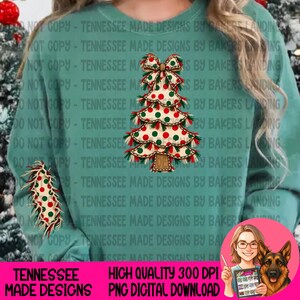 Puede incluir: Una sudadera de cuello redondo color verde azulado con un gráfico central de un árbol de Navidad con lunares rojos y verdes, rematado con un lazo grande. Un gráfico de árbol más pequeño a juego se sitúa en la manga izquierda.