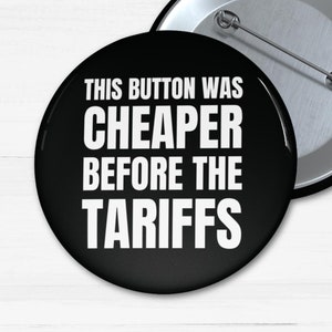 May include: Black button with white text that reads "This button was cheaper before the tariffs".