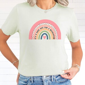 May include: A light green t-shirt featuring a rainbow graphic and the text "It's a good day for a revolution".