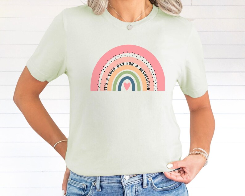 May include: A light green t-shirt featuring a rainbow graphic and the text "It's a good day for a revolution".