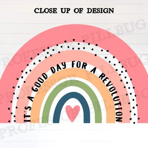 May include: A pink rainbow with a heart in the centre and the text "It's a good day for a revolution" in black lettering.