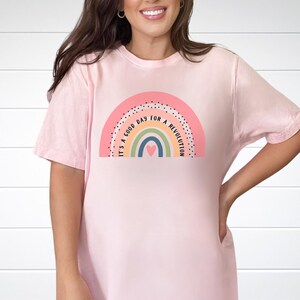 May include: A pink t-shirt featuring a rainbow graphic and the text "It's a good day for a revolution".