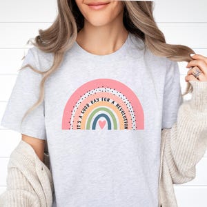 May include: A light grey t-shirt with a rainbow graphic and the text "It's a good day for a revolution".