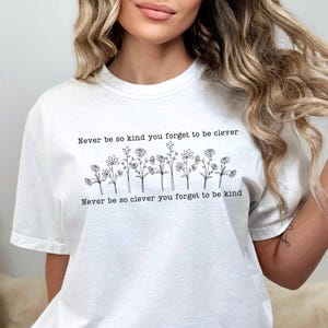 May include: White t-shirt with a black graphic print of flowers and the text "Never be so kind you forget to be clever. Never be so clever you forget to be kind."