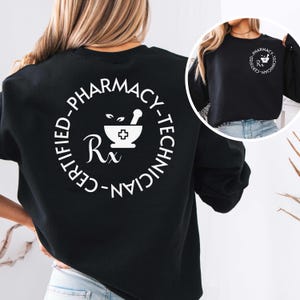 May include: A black long-sleeve sweatshirt featuring a large white circular graphic on the back with the text "CERTIFIED-PHARMACY-TECHNICIAN" surrounding a mortar and pestle icon and "Rx" symbol. A smaller version of the same graphic is on the front.
