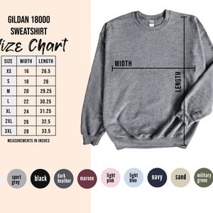 Puede incluir: Una sudadera gris jaspeado Gildan 18000 con una tabla de tallas que muestra las medidas de ancho y largo en pulgadas. La tabla incluye tallas XS a 3XL. Se muestran opciones de color debajo de la tabla.