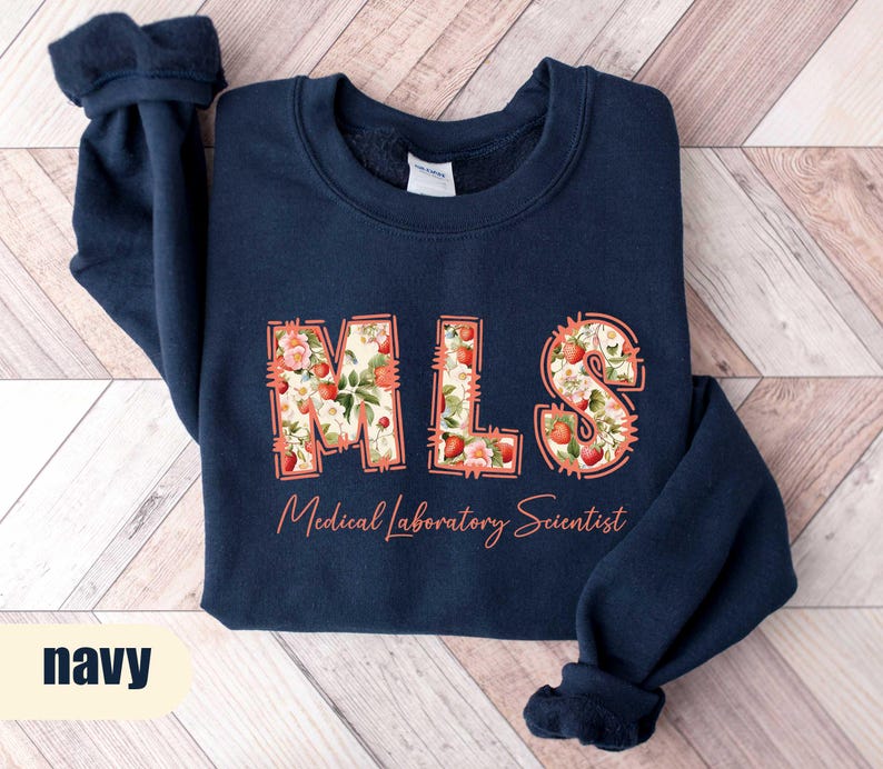Puede incluir: Sudadera azul marino con las letras "MLS" en un dise&ntilde;o floral, con las palabras "Medical Laboratory Scientist" en cursiva. La sudadera es de color azul marino liso.