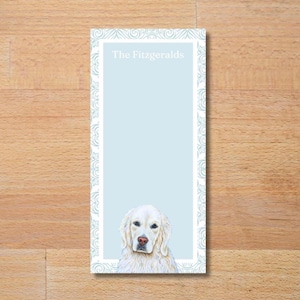 May include: A rectangular notepad with a light blue background and a white decorative border. The notepad features a watercolor illustration of a golden retriever at the bottom and the text "The Fitzgeralds" at the top.