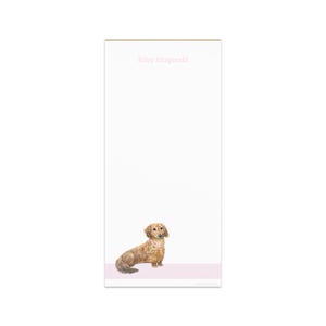 May include: A notepad with a watercolor illustration of a dachshund wearing a pink collar. The notepad has a pink border at the bottom and the name "Riley Fitzgerald" printed in pink at the top.