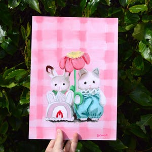 Peut inclure: Peinture fantaisiste repr&eacute;sentant un lapin et un chat anthropomorphes pr&egrave;s d'une grande fleur rose. Le fond est un motif &agrave; carreaux roses. Le lapin porte une tenue blanche avec un arc-en-ciel et une flamme rouge. Le chat porte une salopette bleue.