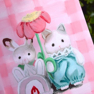Peut inclure: Peinture fantaisiste repr&eacute;sentant deux lapins et une grande fleur. L'un des lapins porte une tenue bleue, l'autre tient un arc-en-ciel. Le fond est un motif &agrave; carreaux roses, cr&eacute;ant une sc&egrave;ne joyeuse et ludique.