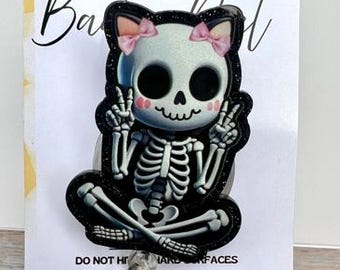 Peut inclure: Un enrouleur de badge squelette noir et blanc avec un design mignon, représentant un squelette avec des nœuds roses et des signes de paix. L'enrouleur de badge porte le texte "Blue Honey Creation".