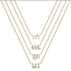 May include: A gold layered necklace with four pendants featuring the numbers 111, 333, 444, and 777, each with a small diamond accent.